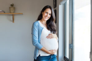 Smiling woman expecting child and looking at camera.