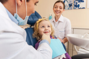 Little girl at dentist looking up and smiling.